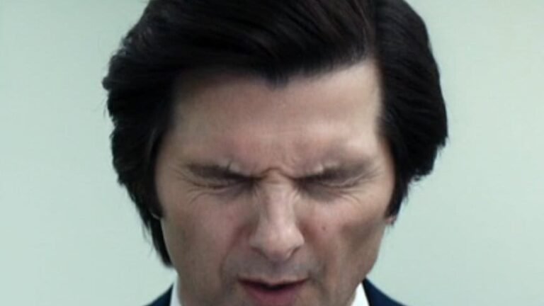 Mark closes his eyes and scrunches his face in a moment of tension inside Lumon. Self-division in Severance