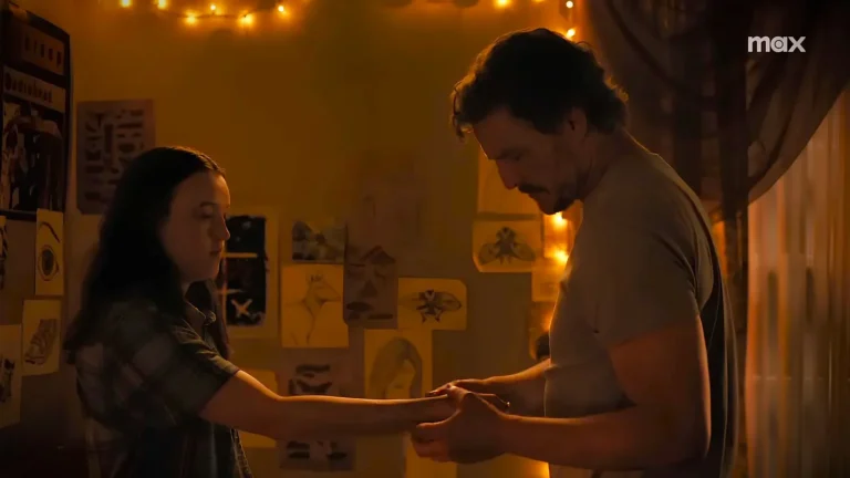 Joel holds Ellie’s arm in a dimly lit room with warm yellow lights, creating an emotional moment in The Last of Us season 2.