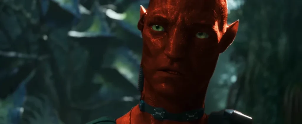 Um Na'vi de pele vermelha com expressão preocupada e olhos verdes intensos, usando um colar tecnológico. - Avatar: Fire and Ash