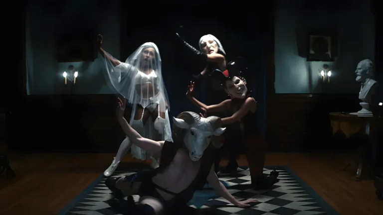 Cena final da Waffle Party em Ruptura: Dylan está sentado de frente para quatro figuras mascaradas, cada uma representando uma emoção da doutrina de Kier. Ele usa a máscara de Kier Eagan e segura um chicote cerimonial, enquanto observa a coreografia enigmática em um ambiente carregado de simbolismo e tensão.