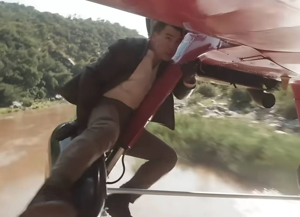 Tom Cruise lutando sobre a asa de um avião bimotor em voo real em Missão: Impossível - Acerto Final Parte 2 (2025).