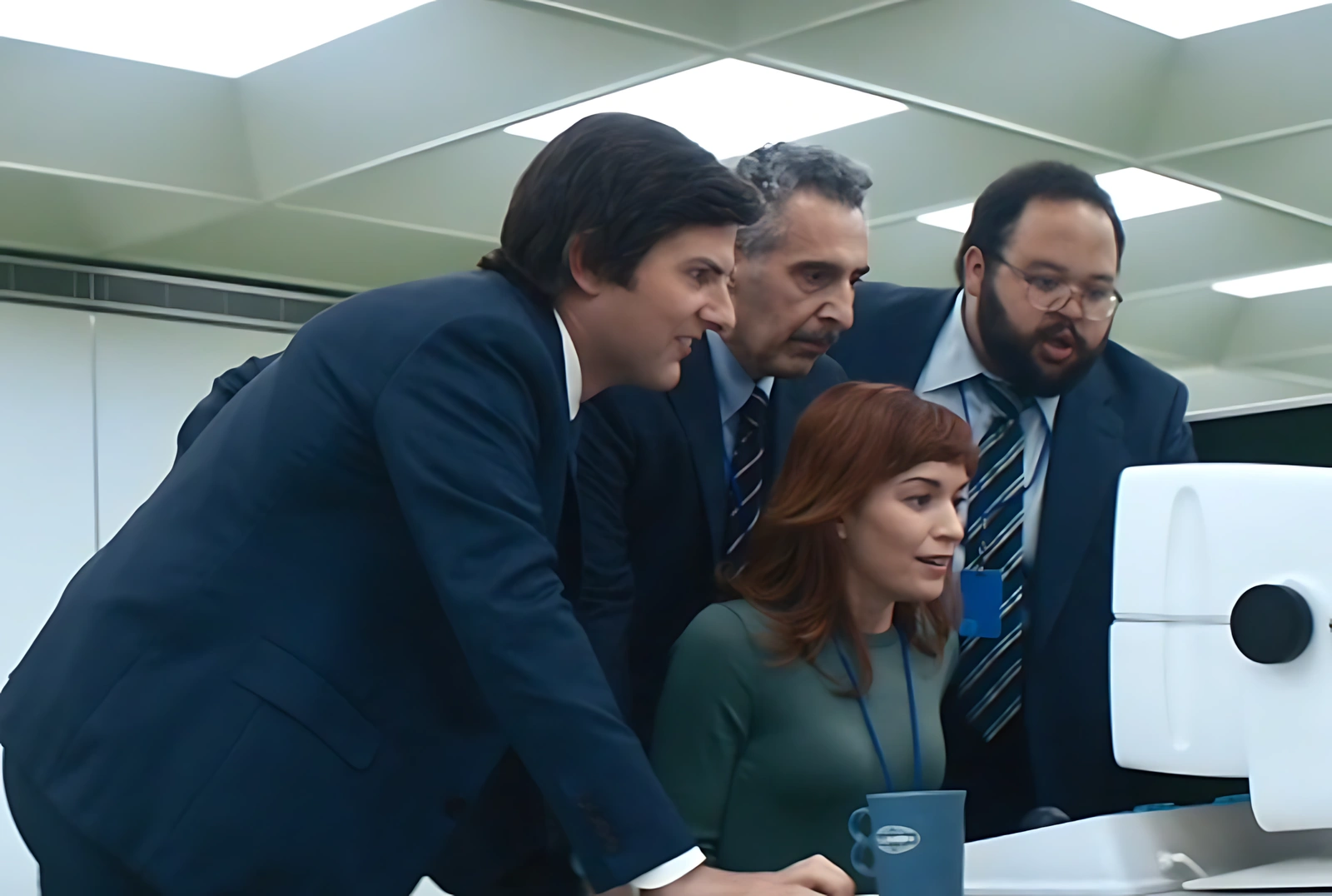 Helly sentada em frente ao computador após finalizar o refinamento dos dados da sala SIENA, cercada por Mark, Irving e Dylan, que observam a tela com entusiasmo, em cena da série Ruptura.