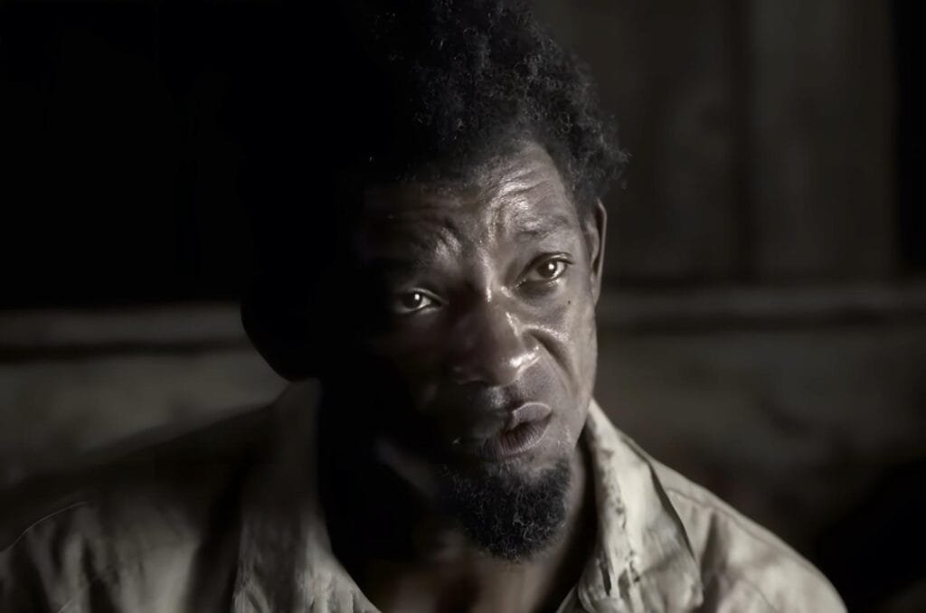 Scene from the film Emancipation shows Peter with an intense expression, lit by soft side lighting, reflecting the pain and dignity of his journey toward freedom. - Apple TV shows about identity