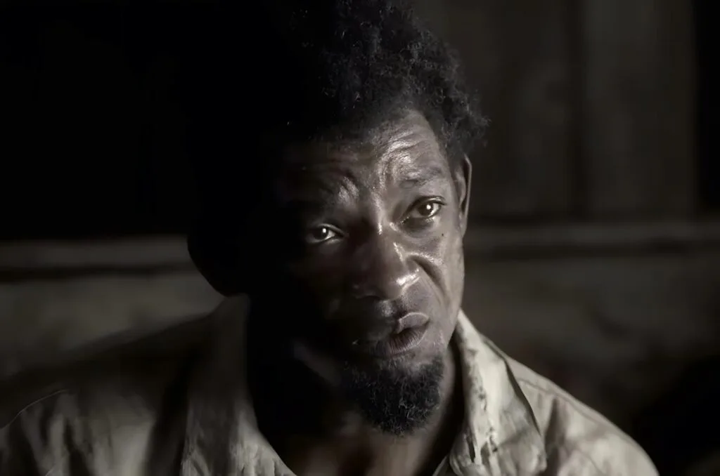 Scene from the film Emancipation shows Peter with an intense expression, lit by soft side lighting, reflecting the pain and dignity of his journey toward freedom. - Apple TV shows about identity