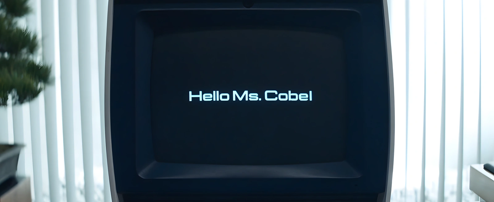 Tela do computador de Milchick exibe a mensagem 'Hello Ms. Cobel', indicando que o sistema ainda não foi atualizado após a saída de Harmony Cobel da Lumon.