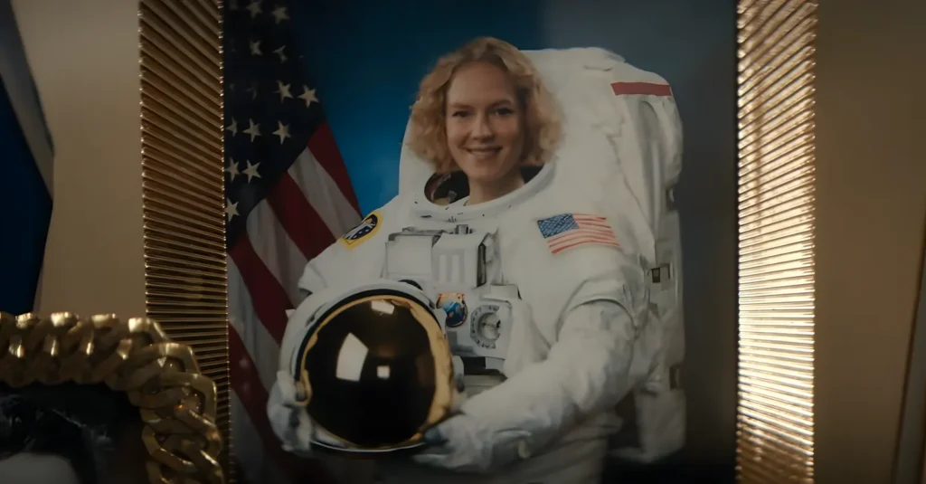 Portrait of Verity dressed as an astronaut, with United States flags in the background, in one of the alternate realities shown in Black Mirror's Bête Noire episode.