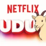 Colorful digital illustration with the word TUDUM in large letters styled like the Netflix brand, with NETFLIX written in red above. A cartoon goat appears coming out from the letter 'U', looking curiously at the viewer. The image references Netflix's iconic sound, which was almost replaced by the sound of a goat. - Origin of the name Tudum