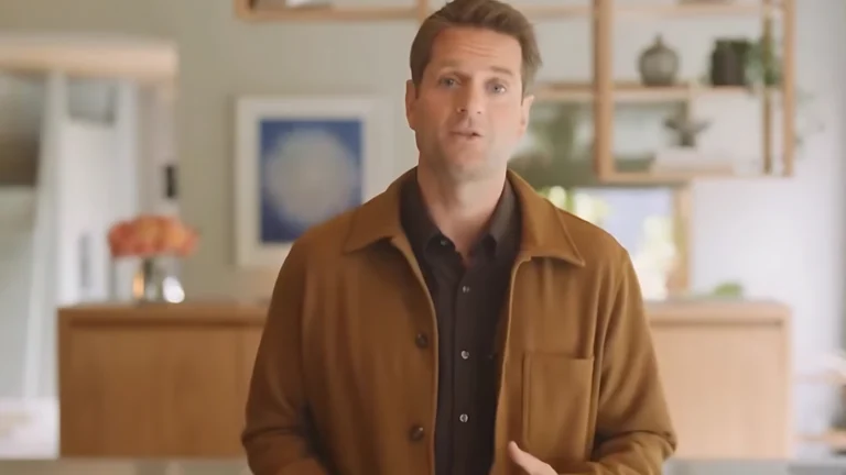 AI avatar of Klarna CEO Sebastian Siemiatkowski presenting the company's earnings in an official video. He wears a brown jacket in a modern home setting. CEO de IA na Klarna