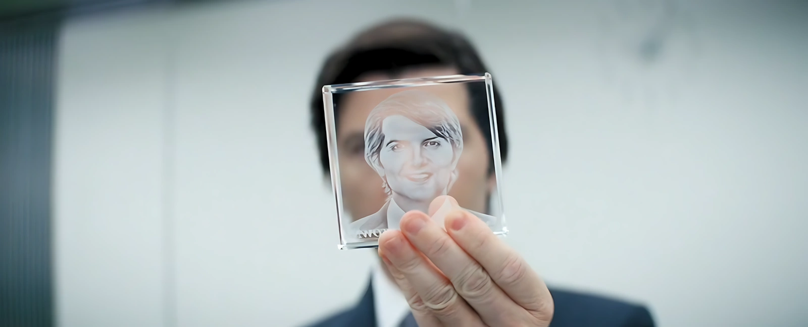 Mark holds and polishes his glass cube with his own face, reflecting on the meaning of the award in the series Severance.