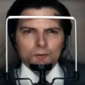 Mark undergoes a disturbing procedure with a device attached to his face, showing tension and confusion in episode 2x03 of the series Severance. Wires and sensors connected to his face suggest a psychological test or interrogation.