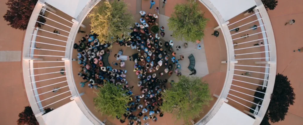 The infected surround Carol in Pluribus during a collective emotional collapse, visually forming a pattern that resembles a question mark.