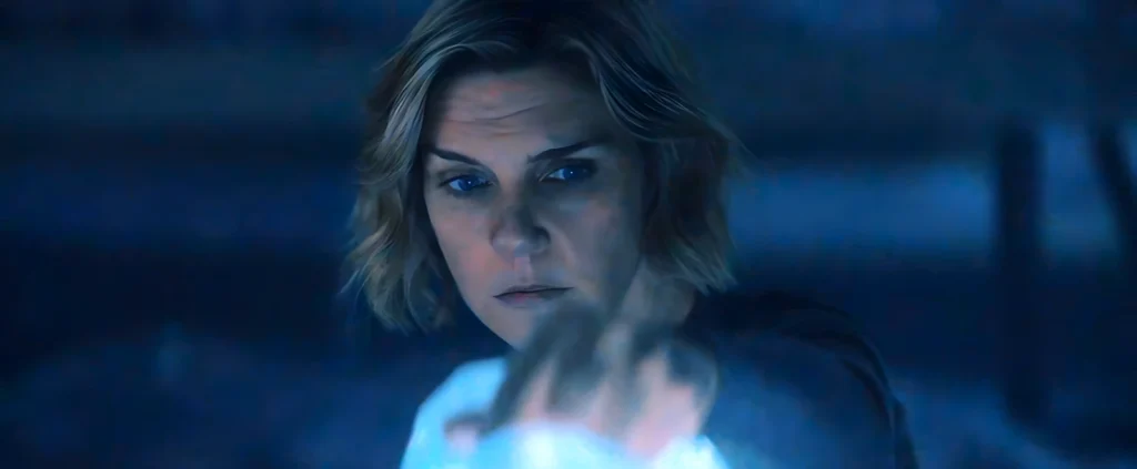 Carol stares intently at an illuminated screen as she discovers the origin of the milk consumed by the infected, made from the protein of people who died, a central revelation of the “Got Milk” arc in the series Pluribus.