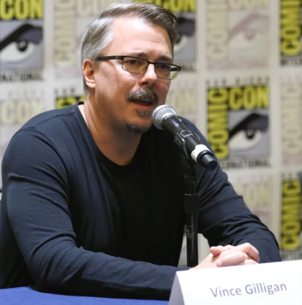 Vince Gilligan speaks into a microphone during a public panel, known as the creator of series that explore moral dilemmas, identity, and human transformation.